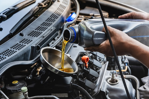 A man conducting a motor oil change as a part of seasonal car care.